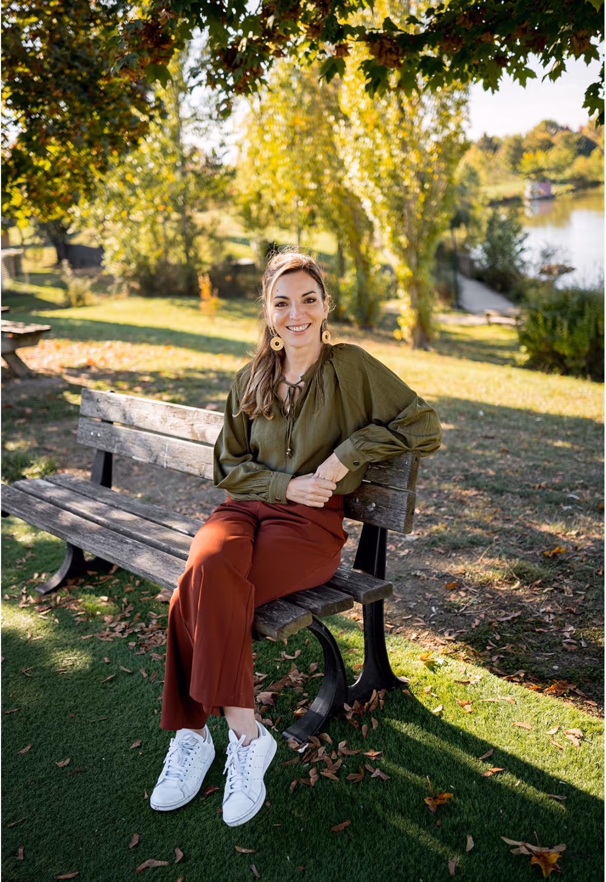 Mélissa Vidal, psychologue, assise sur un banc en extérieur, souriante et regardant l'objectif, illustrant les consultations de thérapie en ligne.